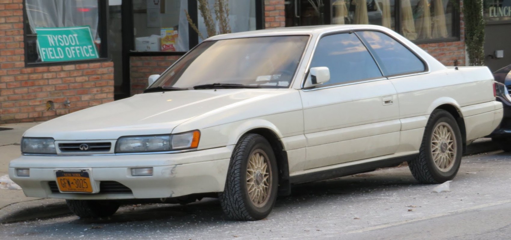 Front-side view of two-door coupe with rectangular headlights and gold mesh wheels