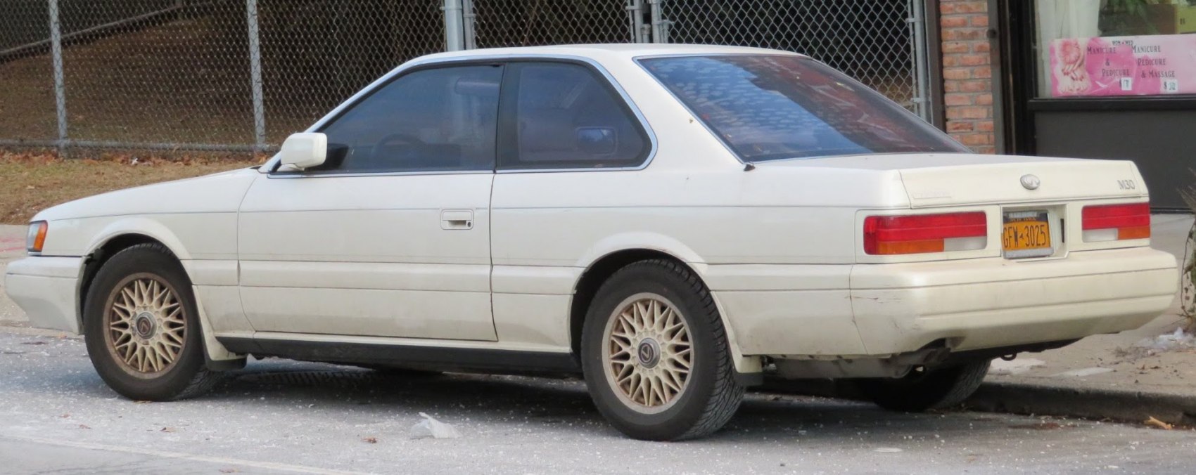 White coupe with distinctive alloy wheels showing side profile