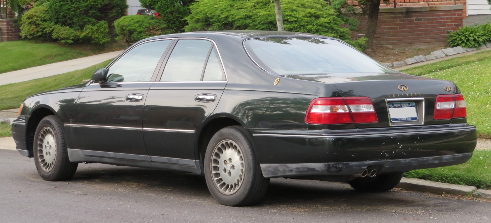 Rear side view of black luxury sedan with distinctive taillights and vintage wheel design.