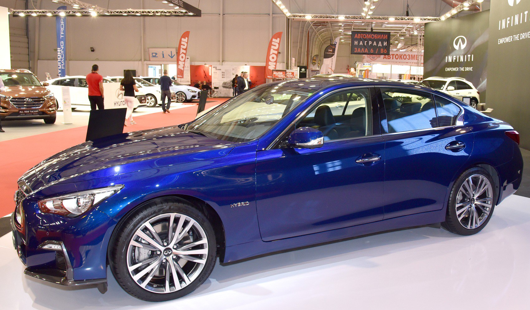 Side view of a blue hybrid luxury sedan with alloy wheels and sharp headlights