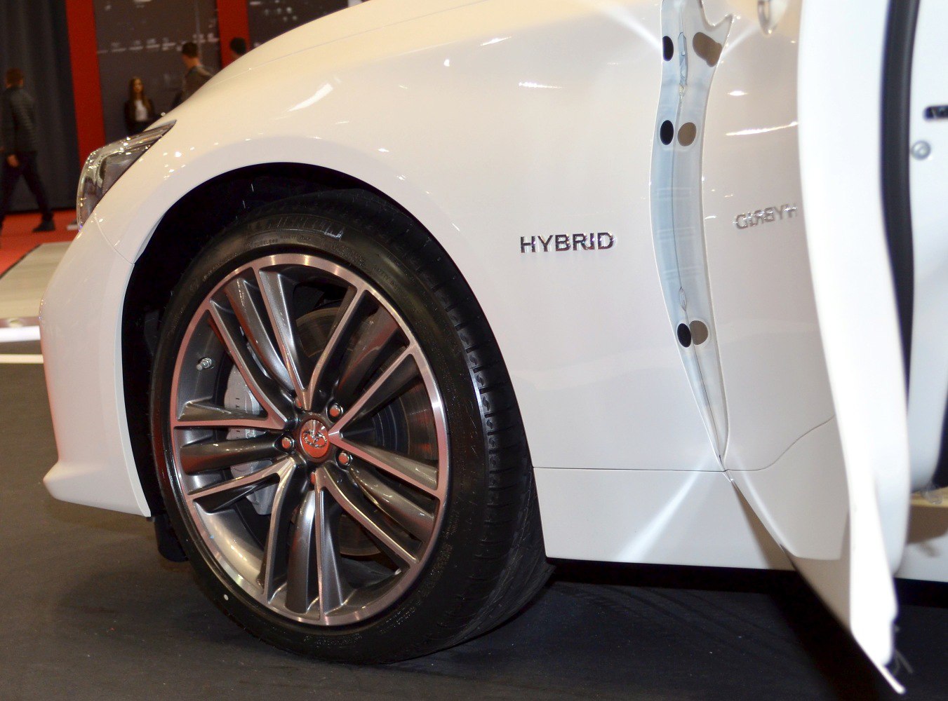 Close-up of alloy wheel and hybrid badge on white car side