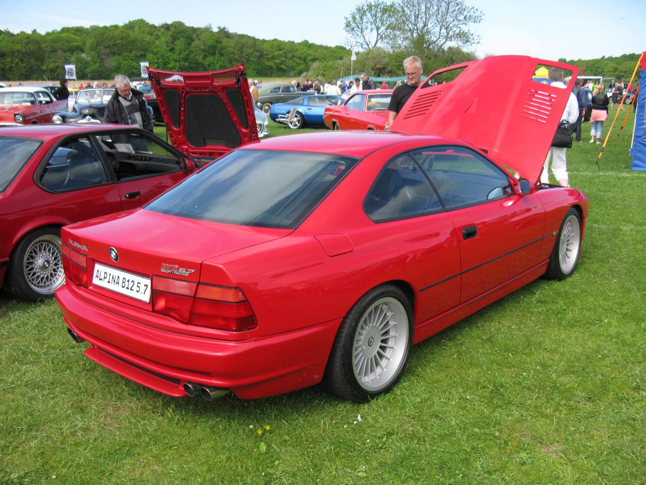 Red coupe rear view with distinctive rims and open front hood