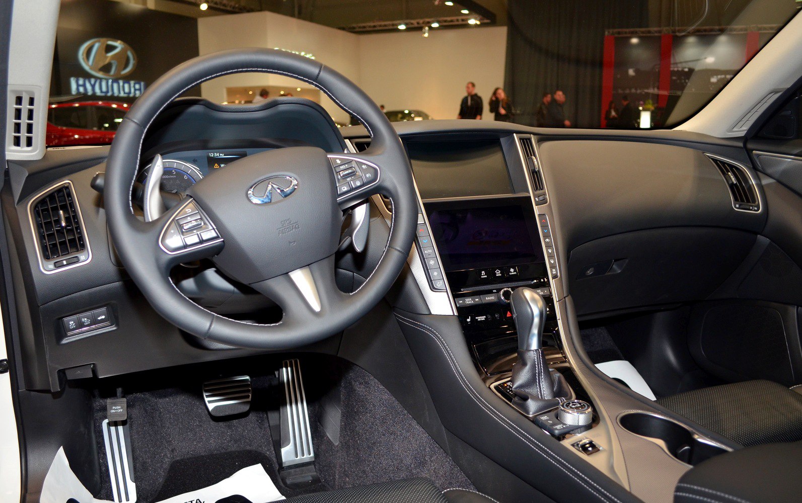 Steering wheel, touchscreen dashboard, gear shift, and pedals.