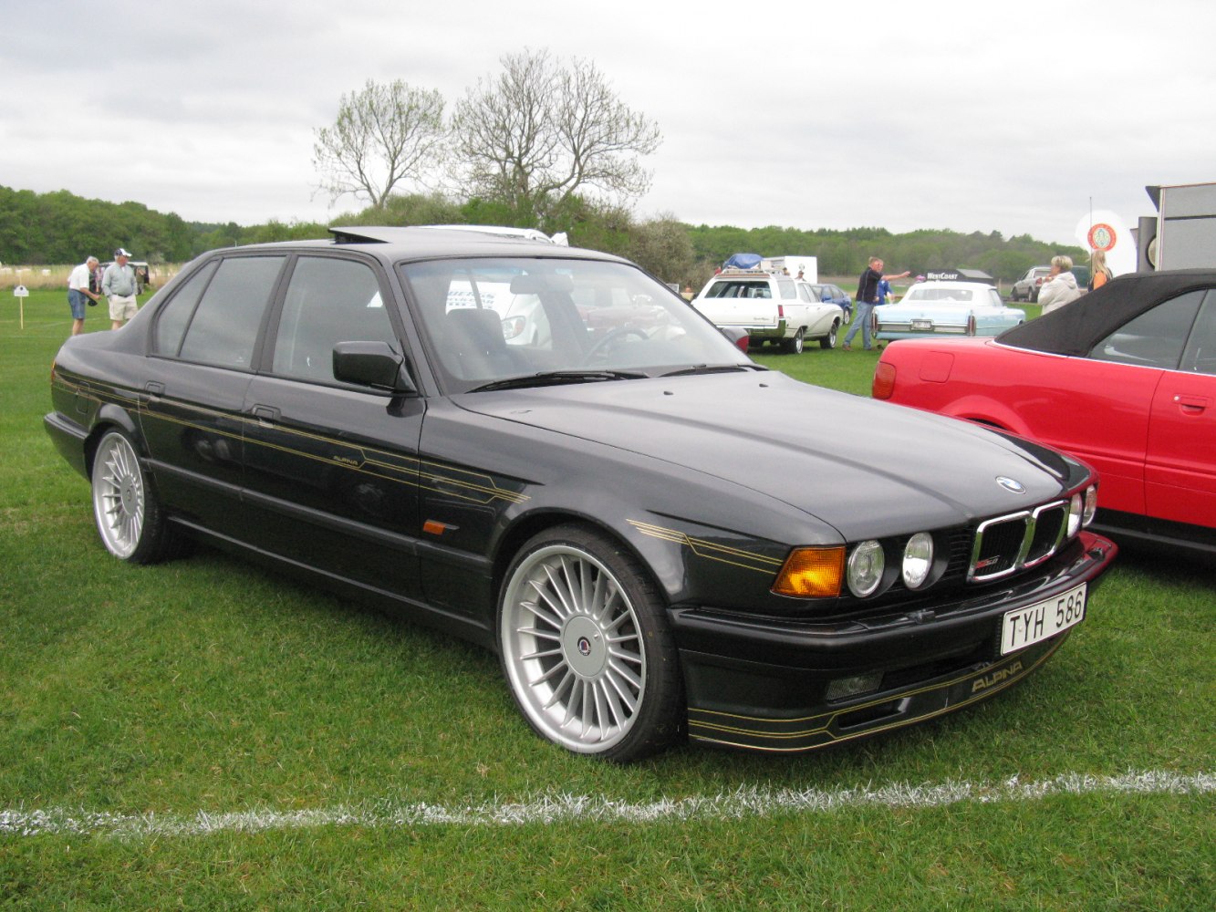 Black sedan with multi-spoke alloy wheels and distinctive side striping