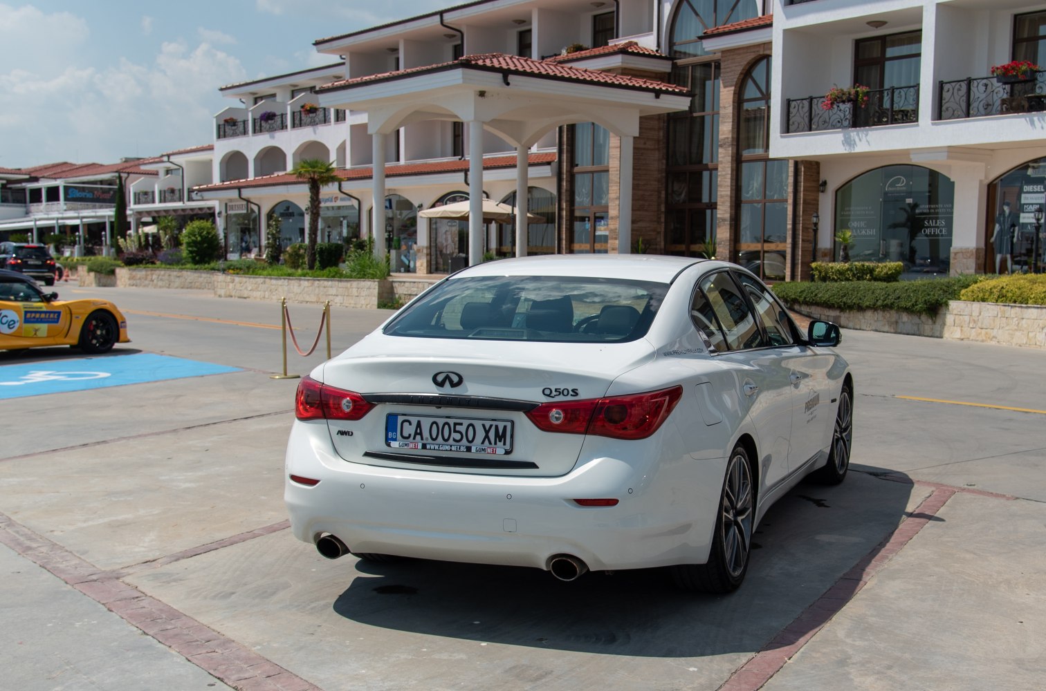 White sedan rear with dual exhaust and distinctive taillights