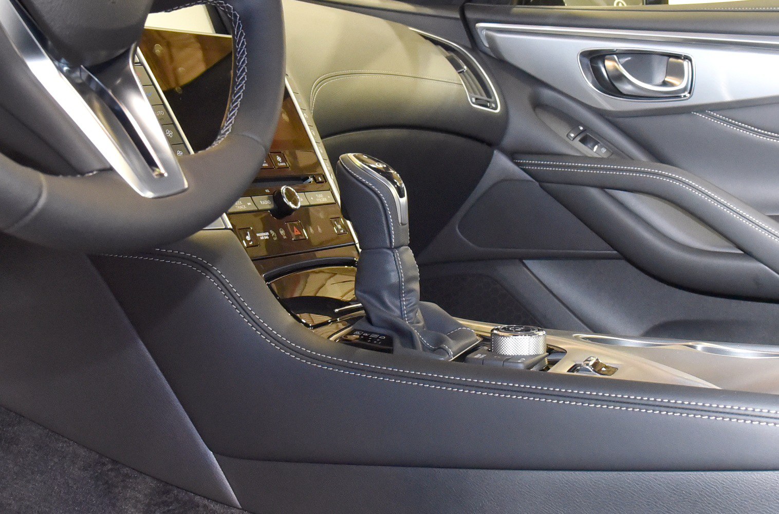 Gear shift lever with stitched leather and control knob in luxury car interior.