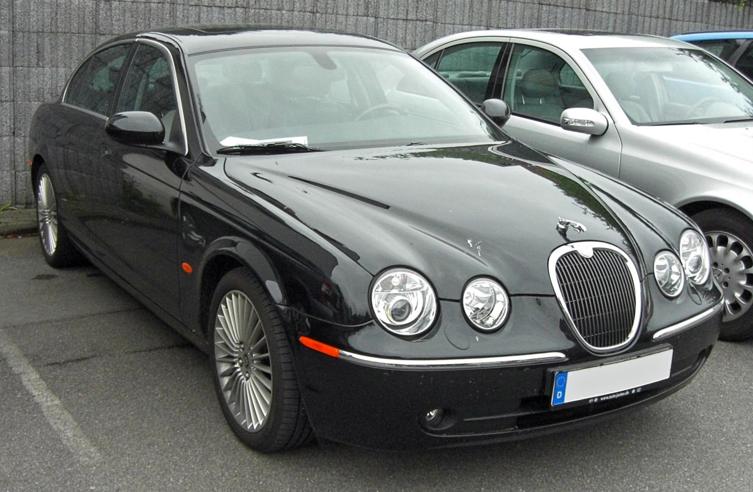 Front and side view of black luxury sedan with round headlights