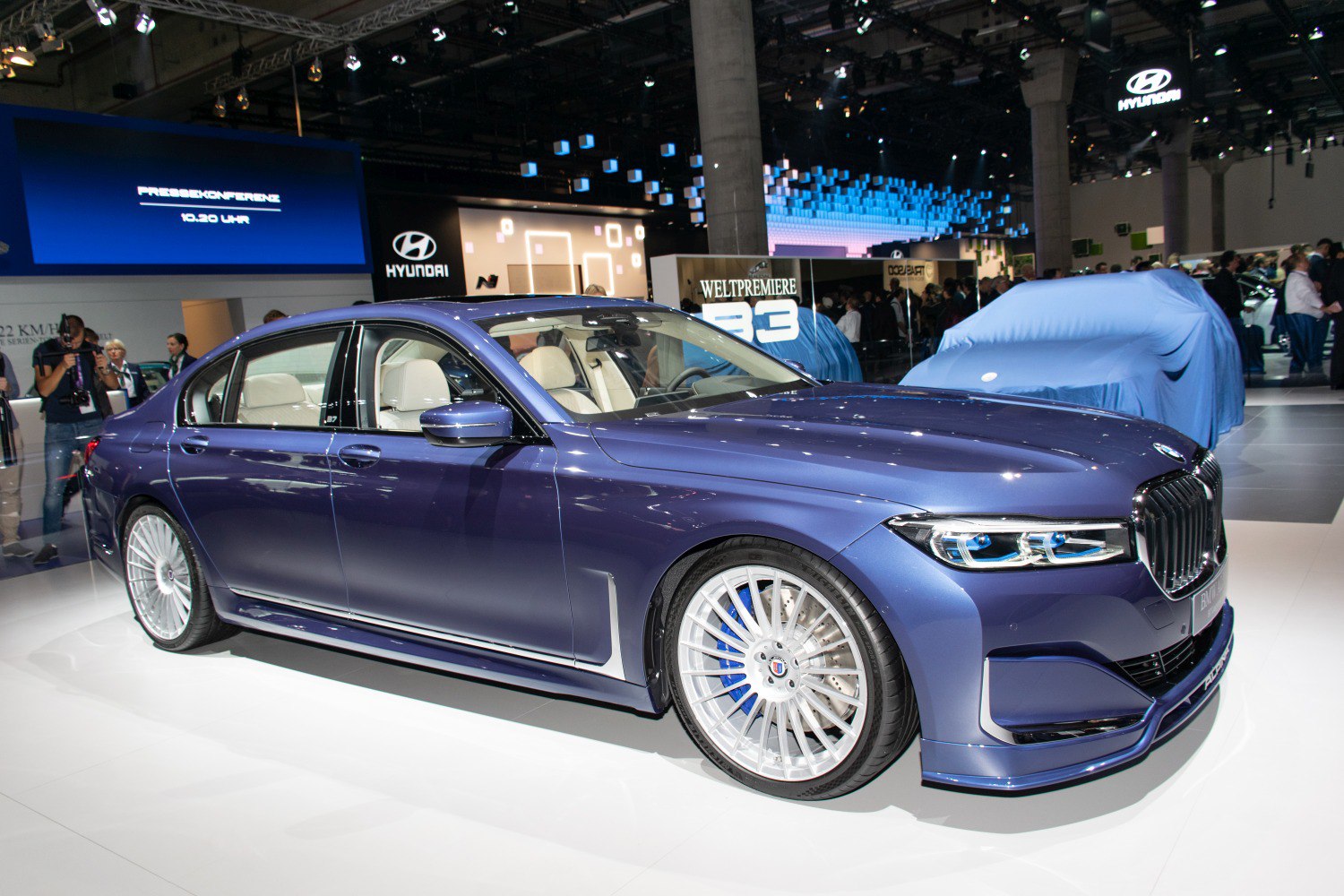 Blue luxury sedan with multi-spoke wheels and aerodynamic design
