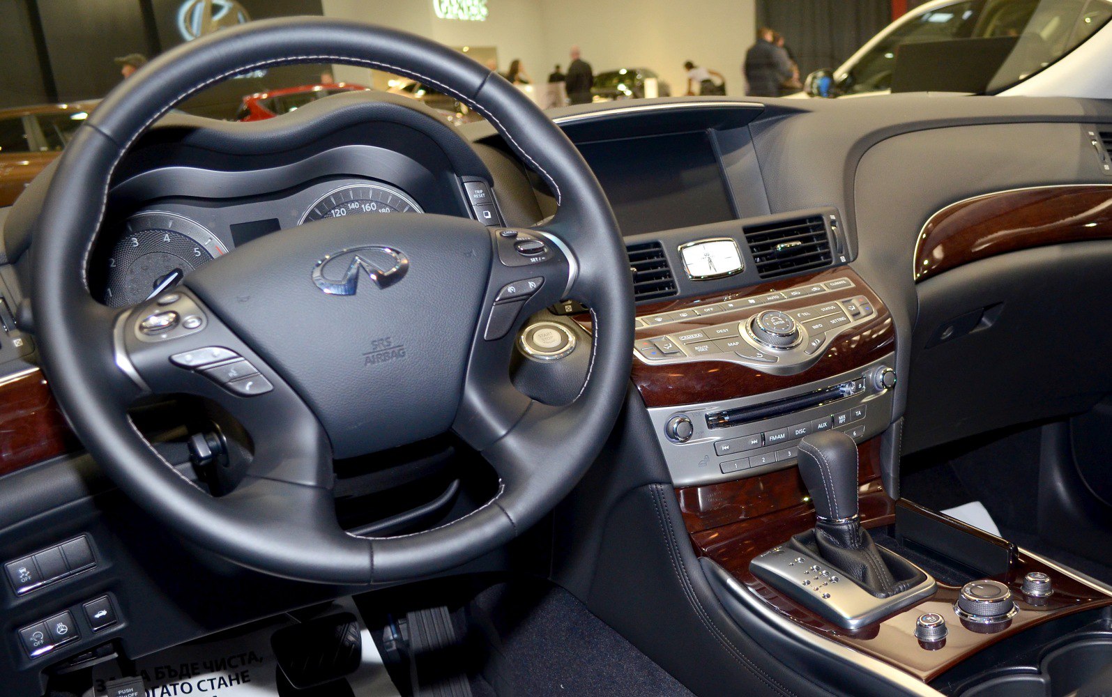 Luxury car interior dashboard and steering wheel with wood trim and controls