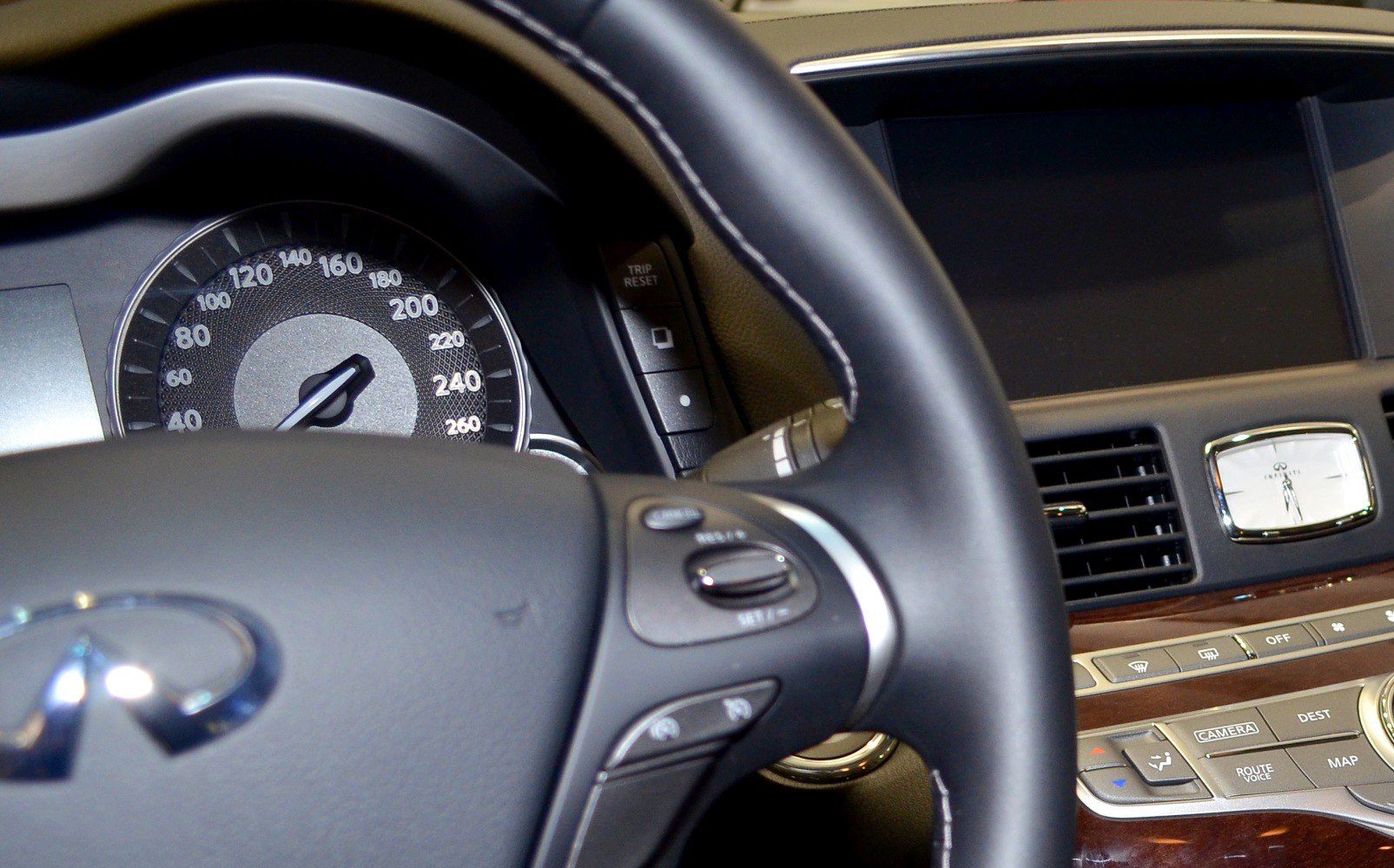 Steering wheel, speedometer, and dashboard controls with analog clock and wood trim