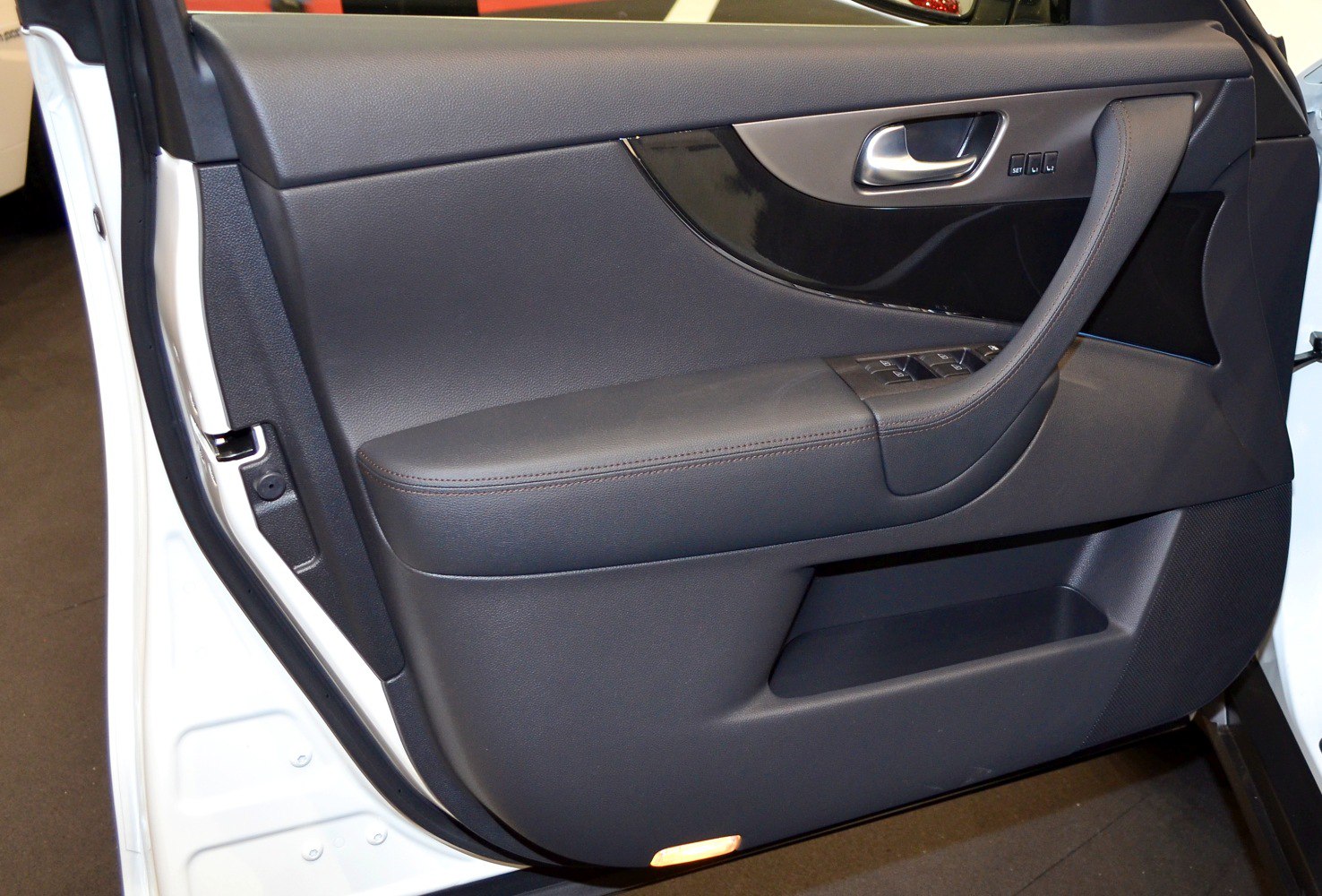 Leather-trimmed car door panel with control buttons and integrated door handle