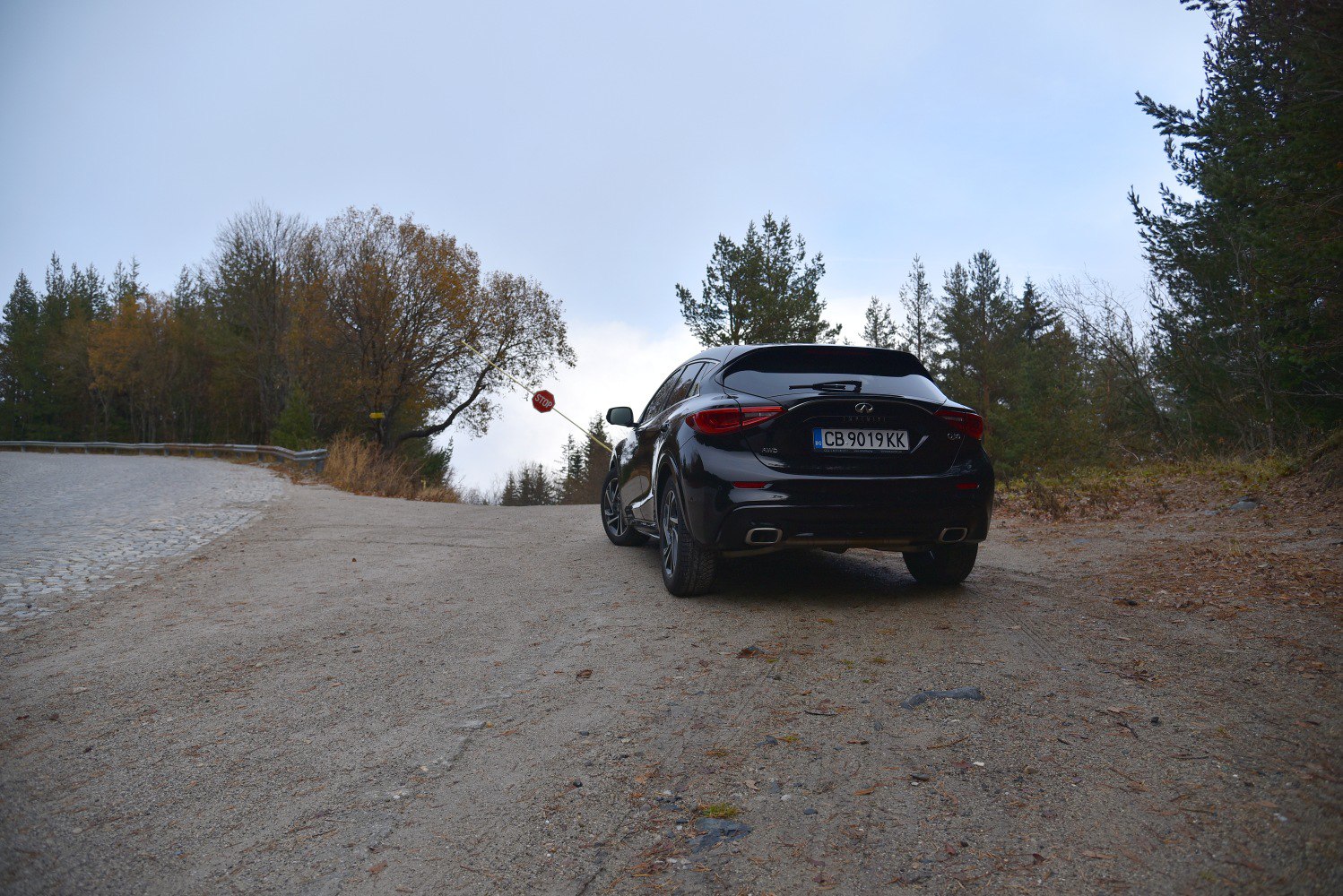 Rear view of hatchback with dual exhausts and sleek taillights on an outdoor gravel road