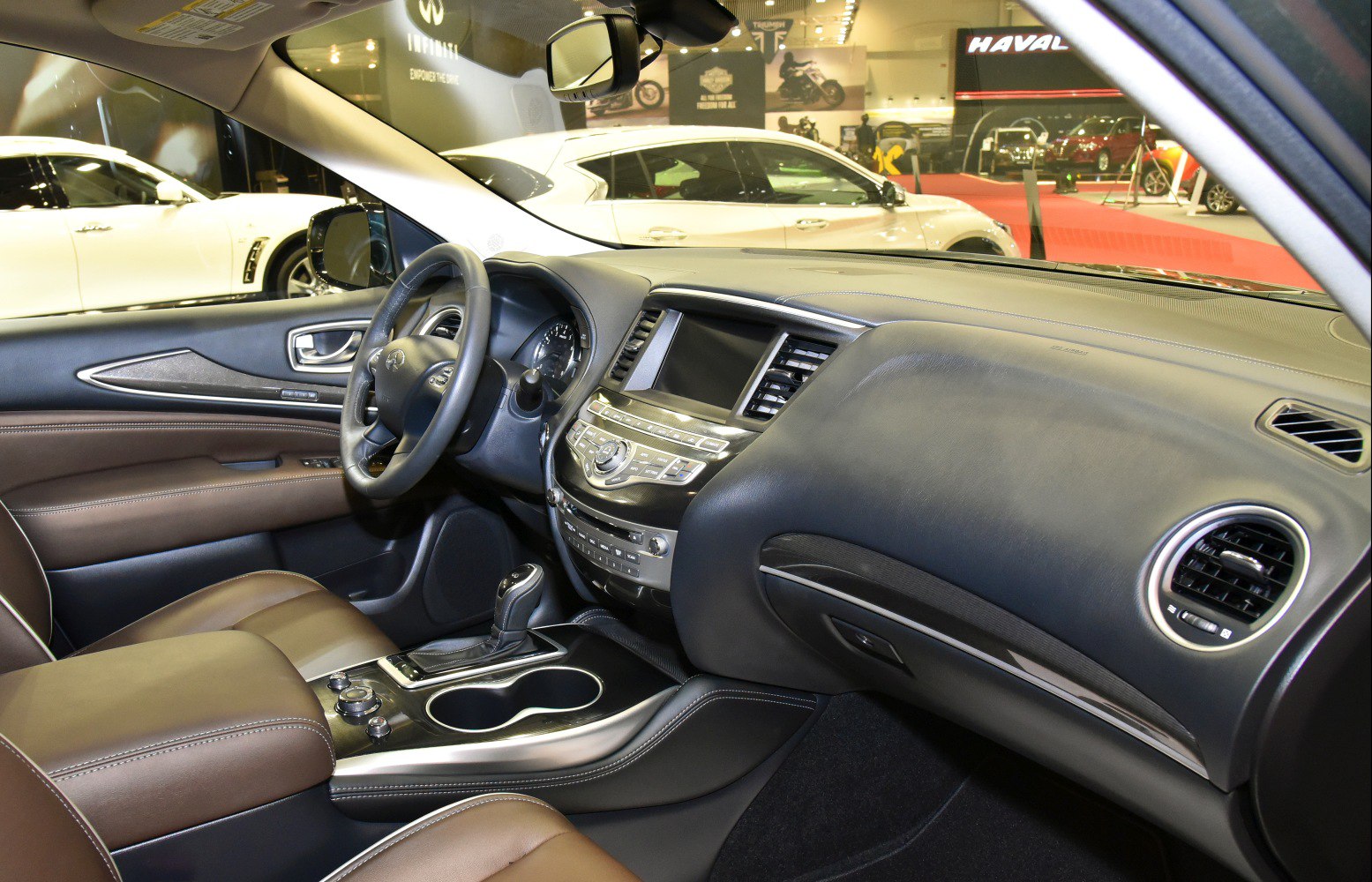 Dashboard, steering wheel, center console, and brown leather seats inside a luxury SUV
