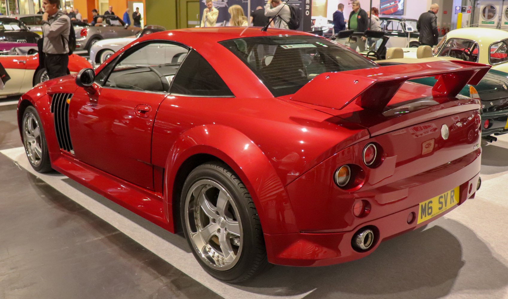 Red sports coupe with large rear spoiler and vented front fender