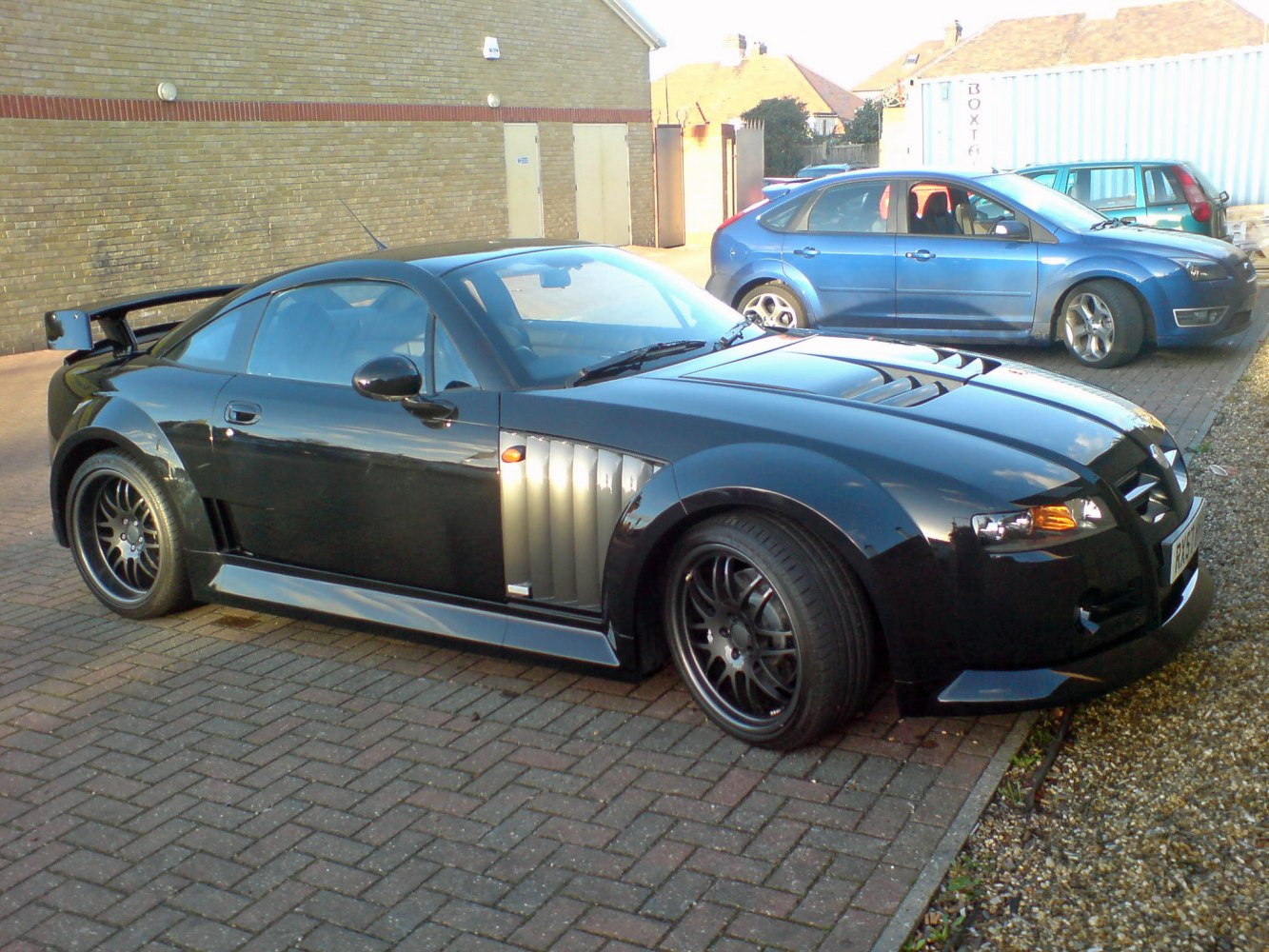 Black sports coupe with side vents and large rear wing spoiler