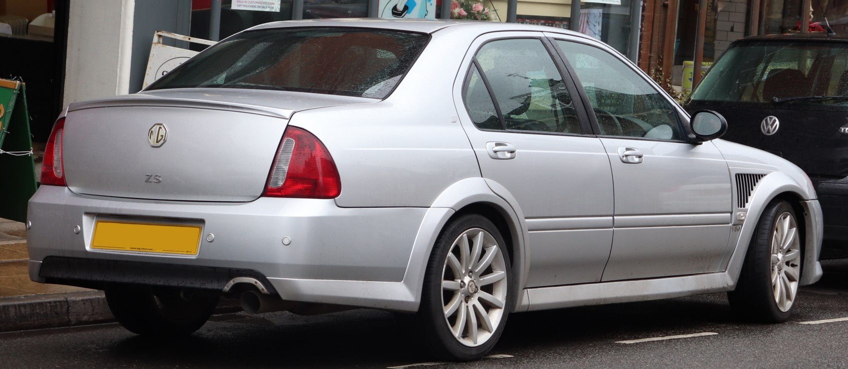 Rear side view with rear spoiler and multi-spoke alloy wheels.