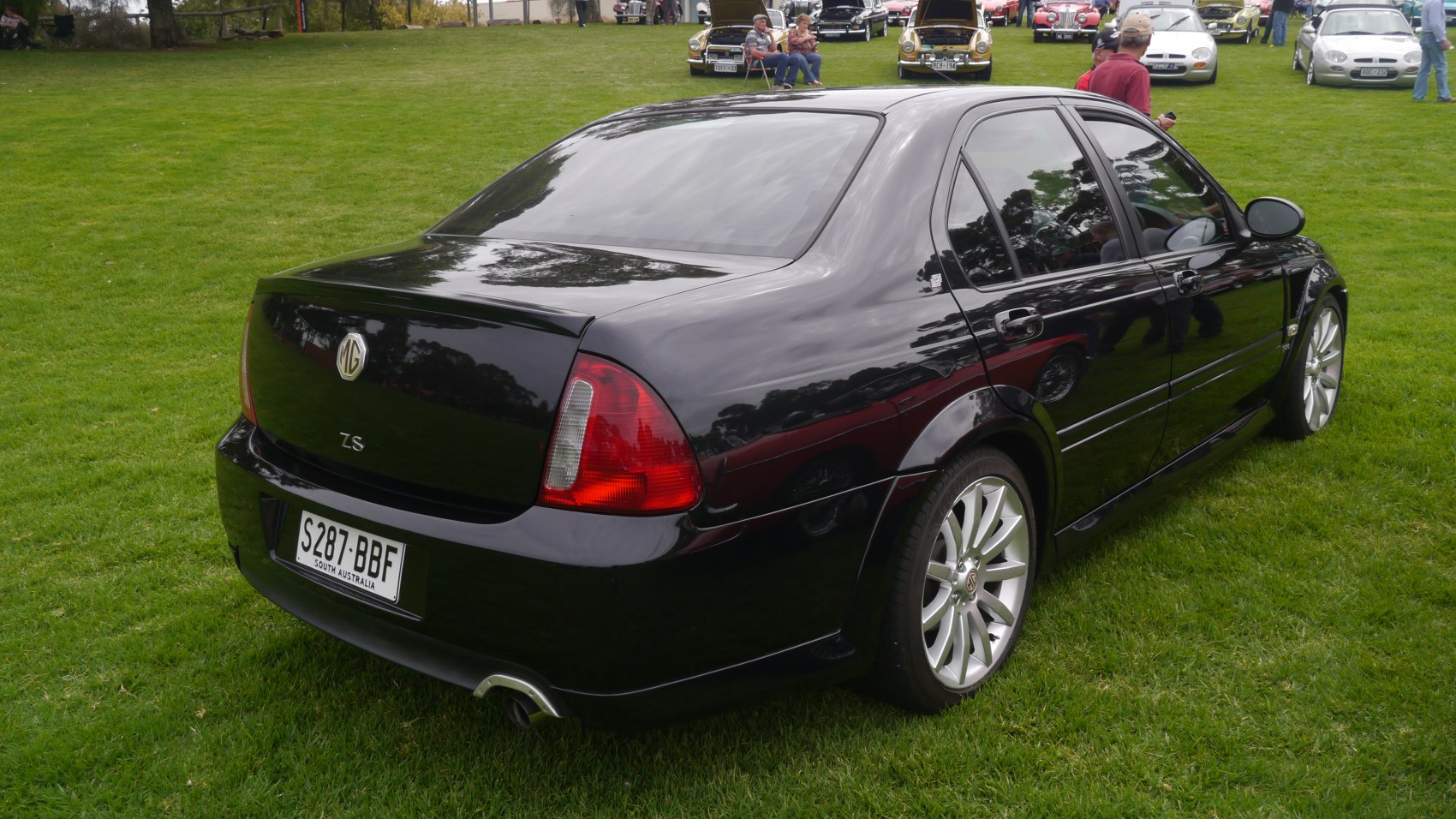 Rear and side view of a black sedan with tinted windows and alloy wheels.
