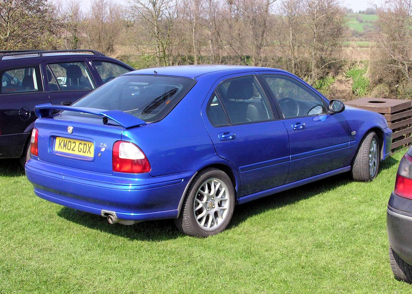 Rear side view of blue hatchback with spoiler and alloy wheels