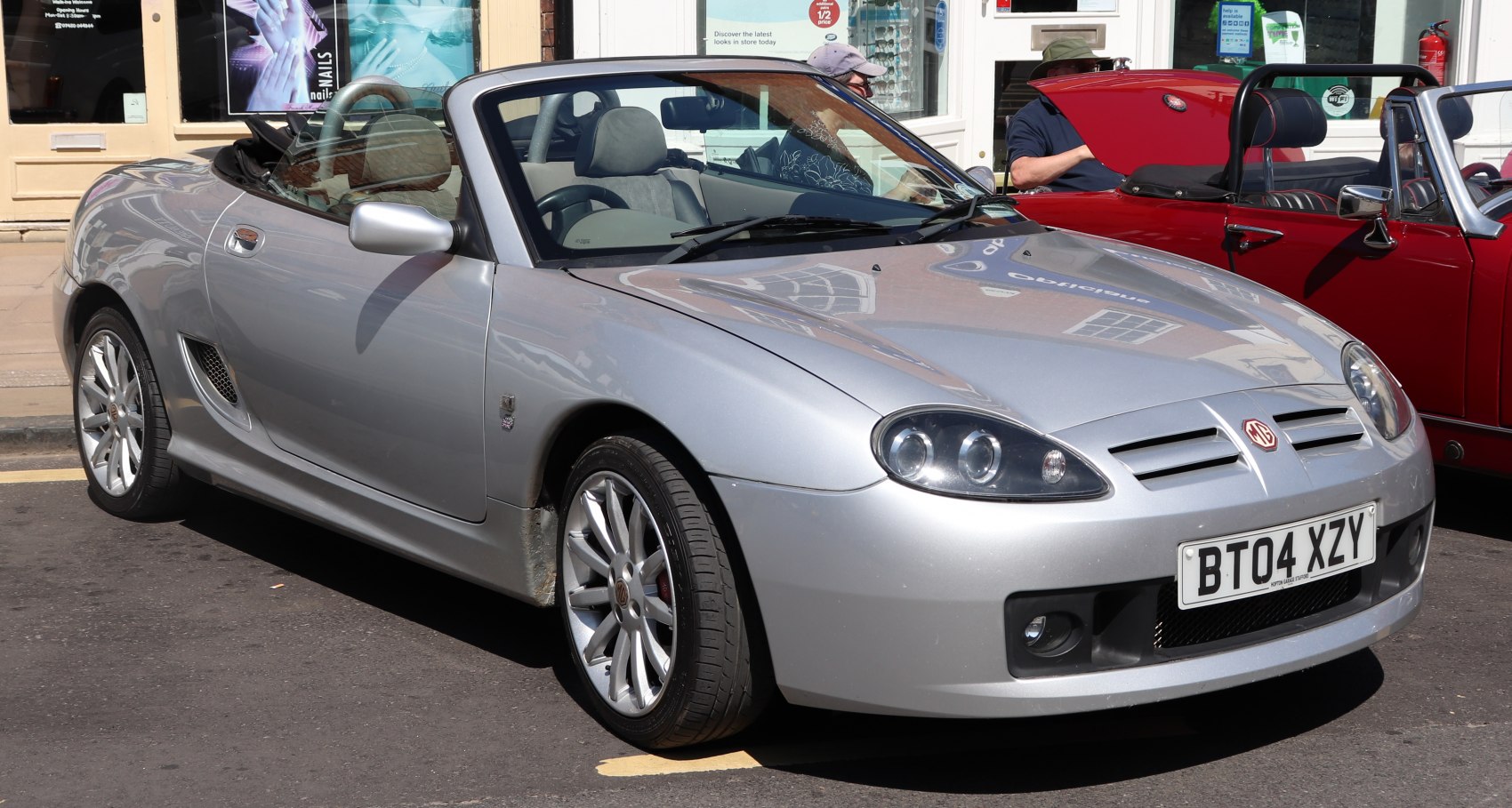 Silver convertible roadster with dual round headlights and alloy wheels