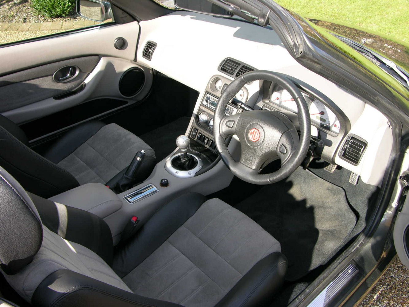 Manual gear shift, steering wheel with emblem, and dashboard view