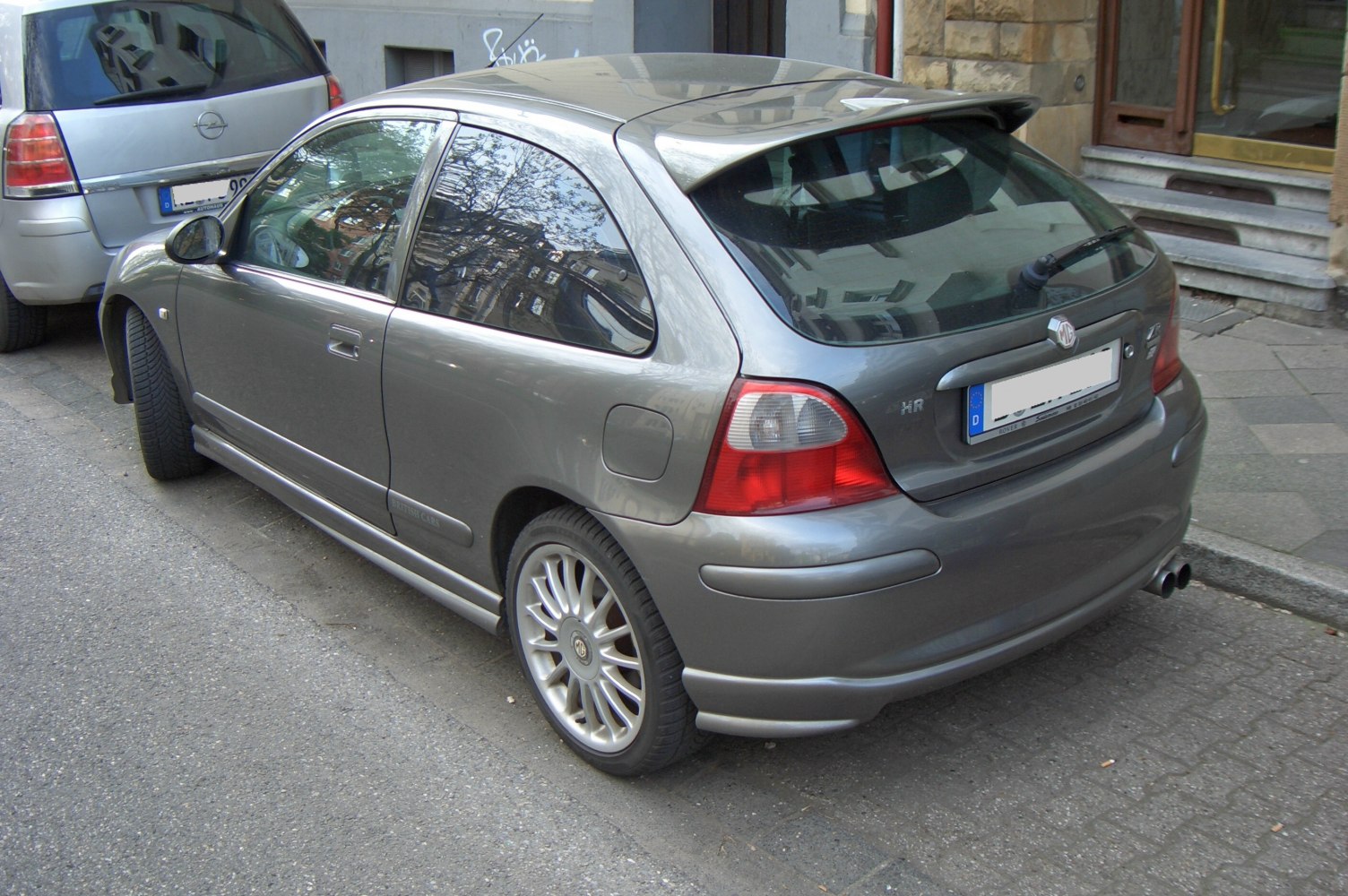 Compact hatchback with rear spoiler, dual exhaust, and alloy wheels