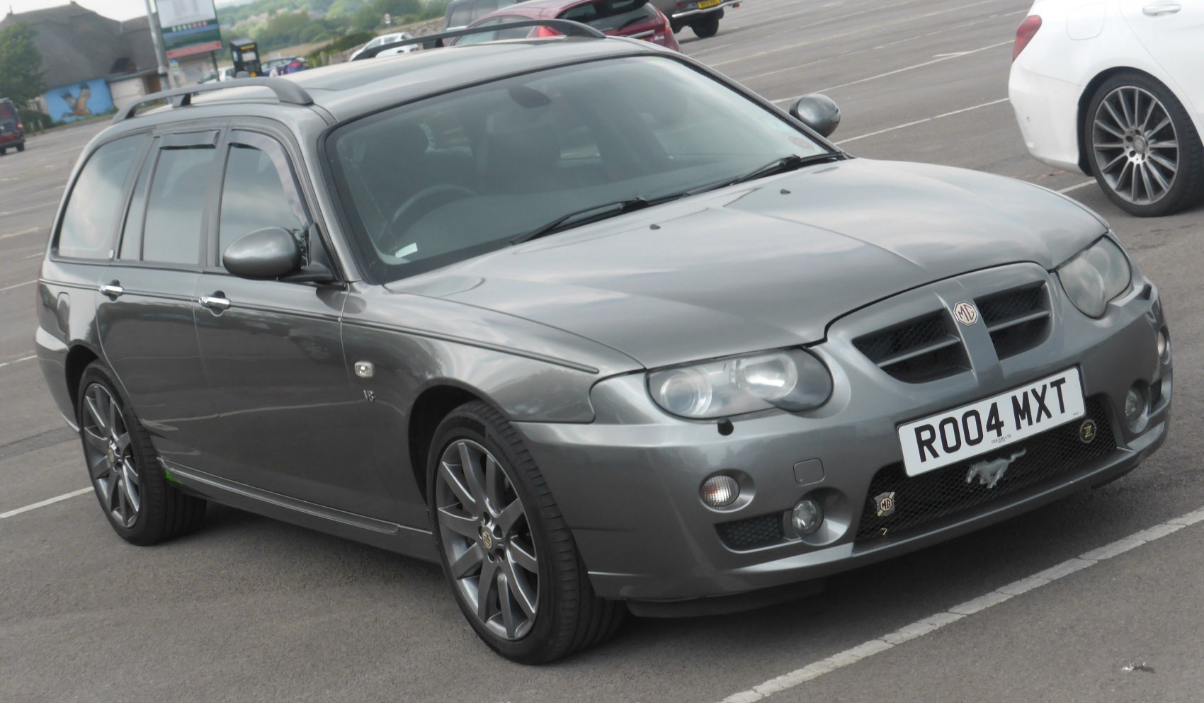 Grey estate car with dual headlamps and alloy wheels, side front view