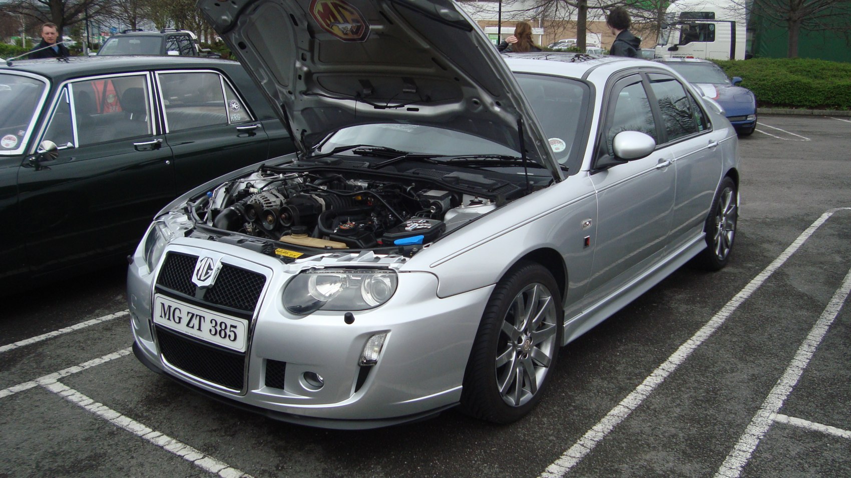 Silver sedan with open hood revealing engine bay and alloy wheels.