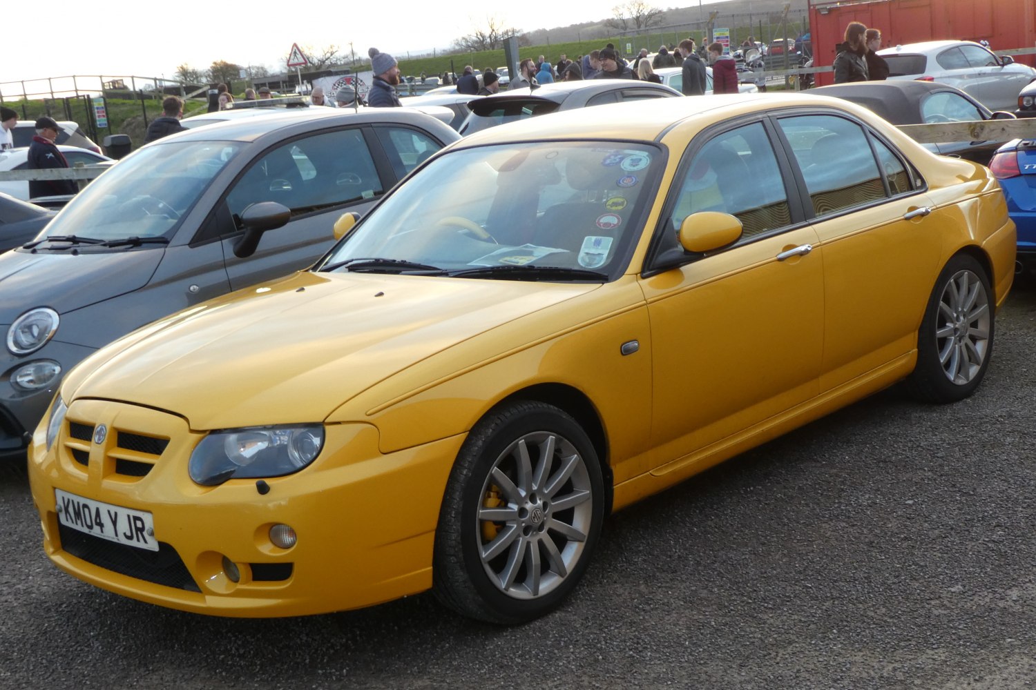 Front three-quarter view of a yellow sporty sedan with alloy wheels