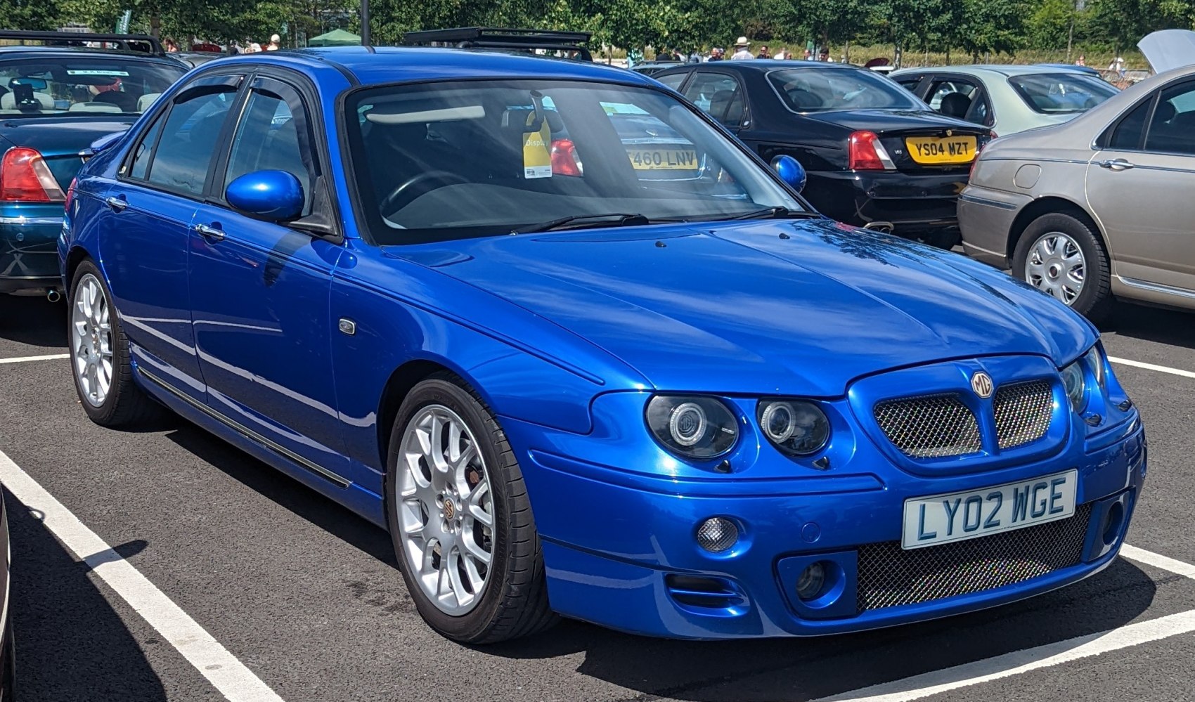 Dual round headlights and sporty mesh grille on blue sedan front angle.