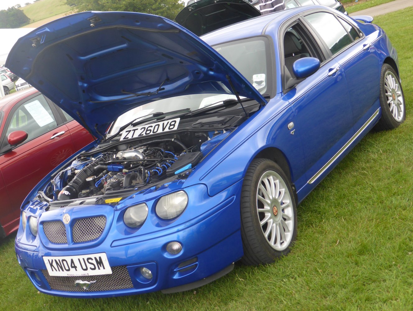 Blue sedan with open hood revealing detailed V8 engine