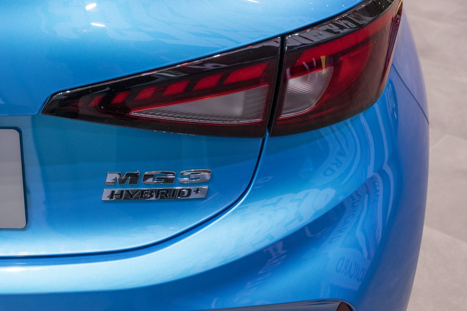 Close-up of rear tail light and hybrid badge on blue car