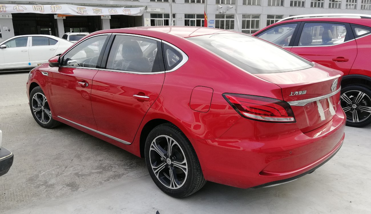 Rear side view of a red sedan with alloy wheels and aerodynamic contours