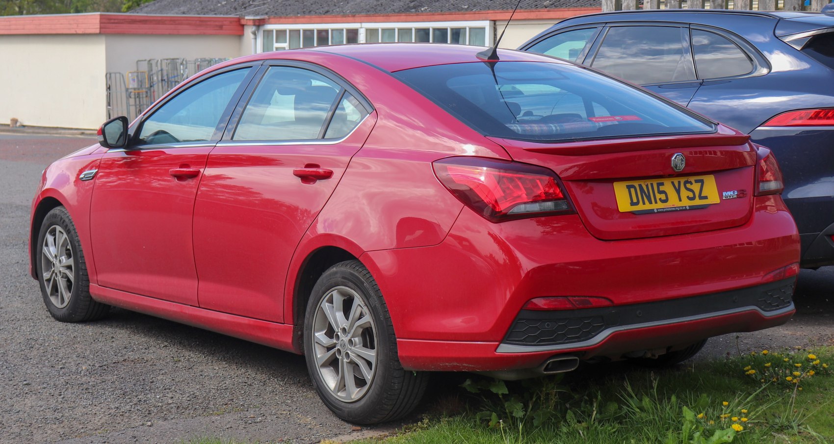 Rear and side view of red sedan with distinctive tail lights and rear bumper