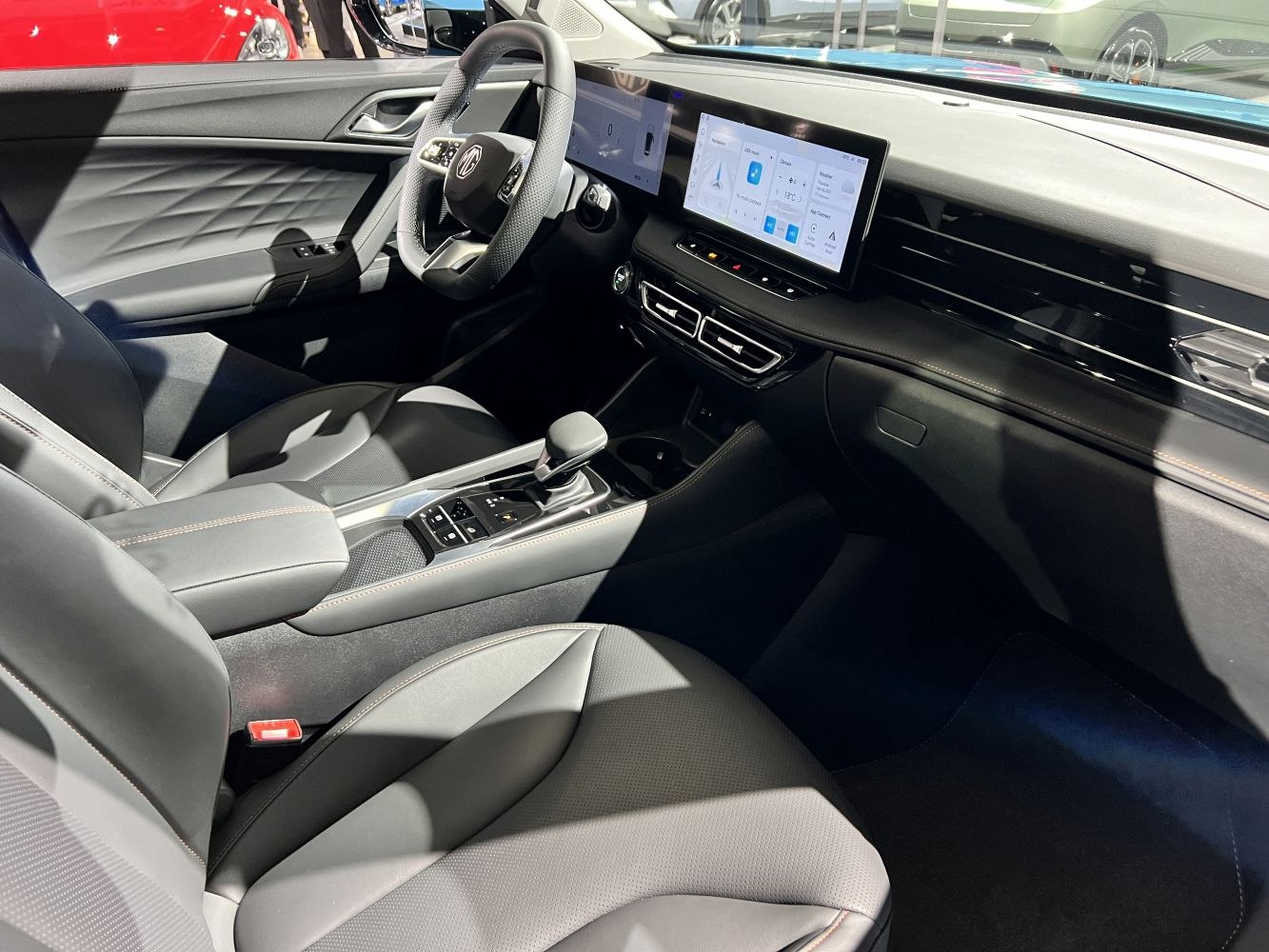 Modern dashboard with large digital displays and leather-wrapped steering wheel