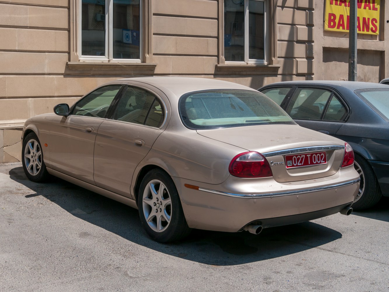 Beige sedan rear view with alloy wheels and chrome trim