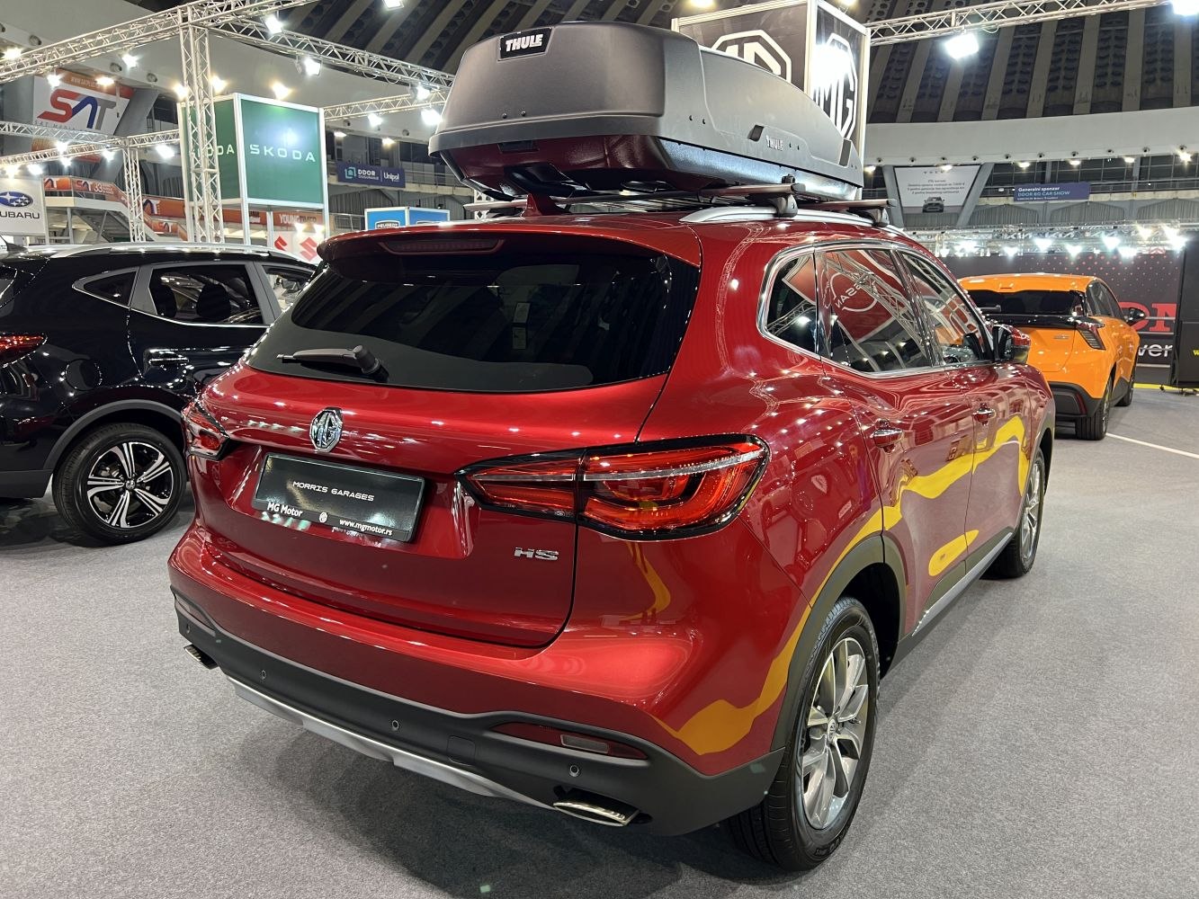 Rear view of red SUV with roof cargo box in exhibition hall
