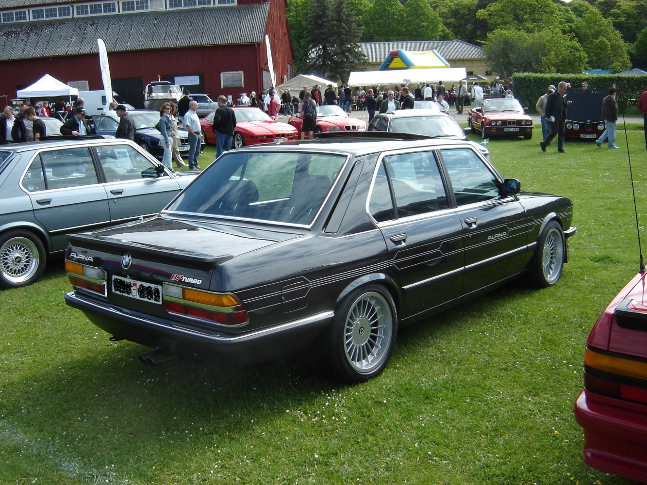 Rear view of a classic Alpina B7 E28 turbo sedan with unique stripes and Alpina multi-spoke wheels