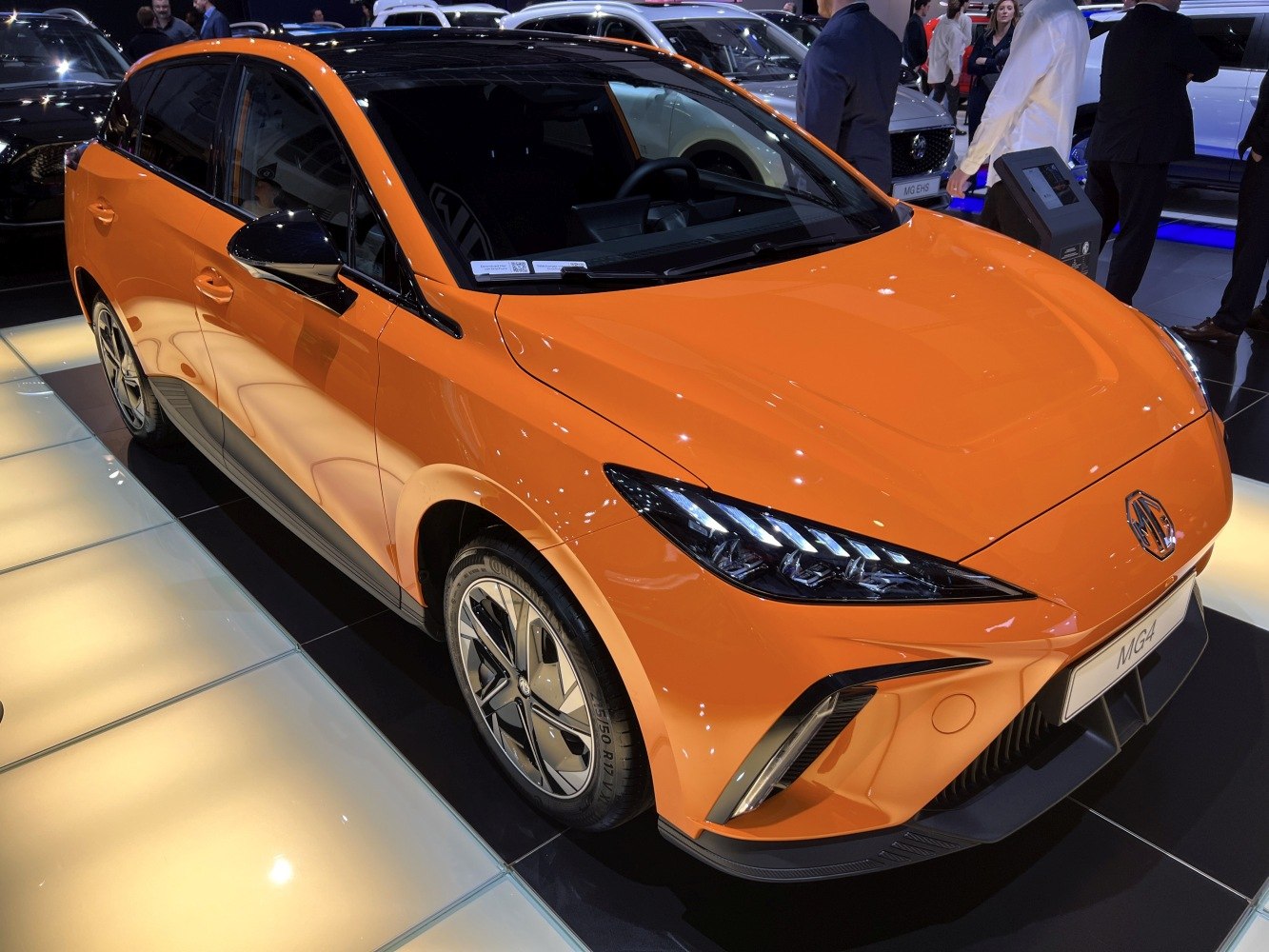 Front-side view of an orange electric hatchback with sleek headlights and alloy wheels