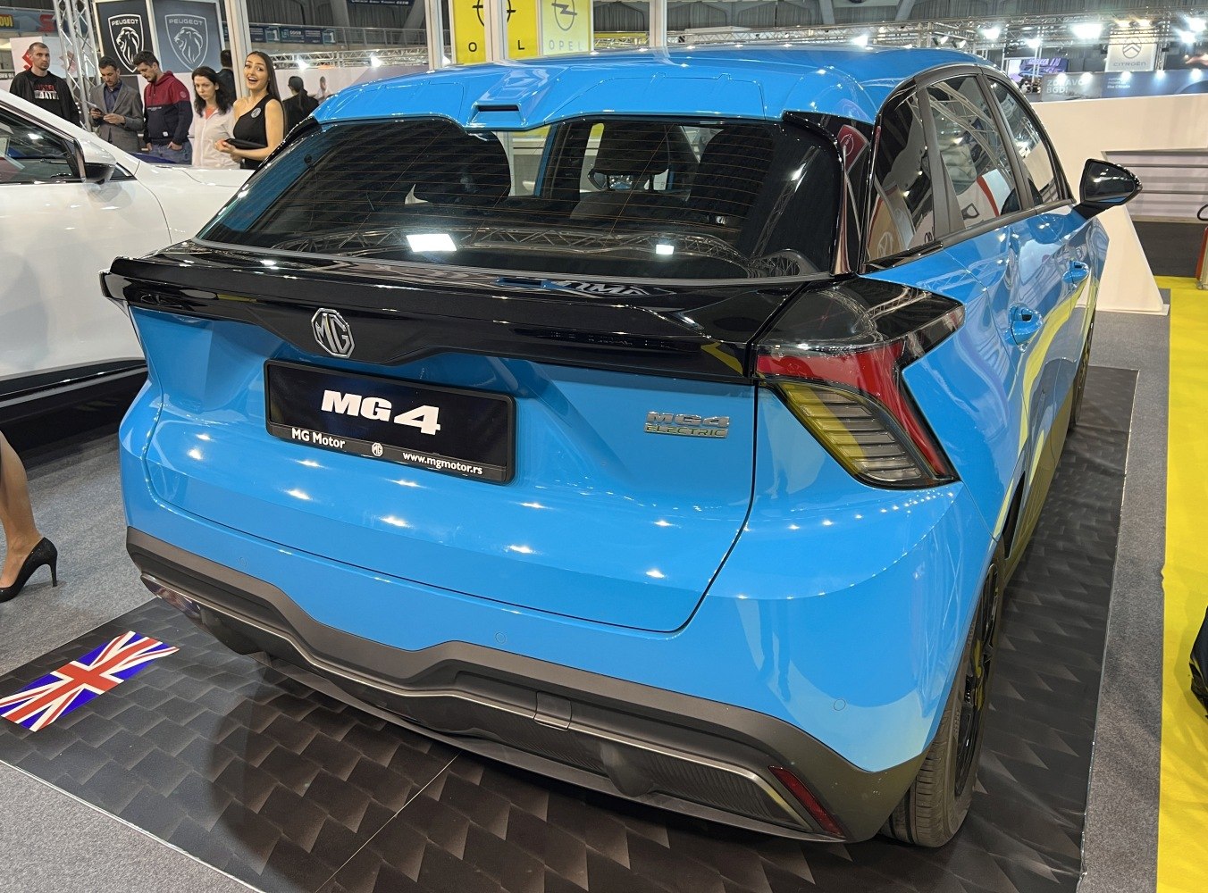 Rear view of blue electric hatchback with black spoiler and modern taillights