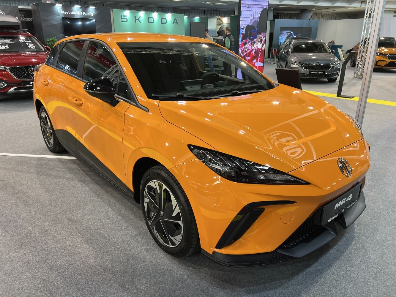 Sleek electric hatchback with modern LED headlights and aerodynamic body in vibrant orange.