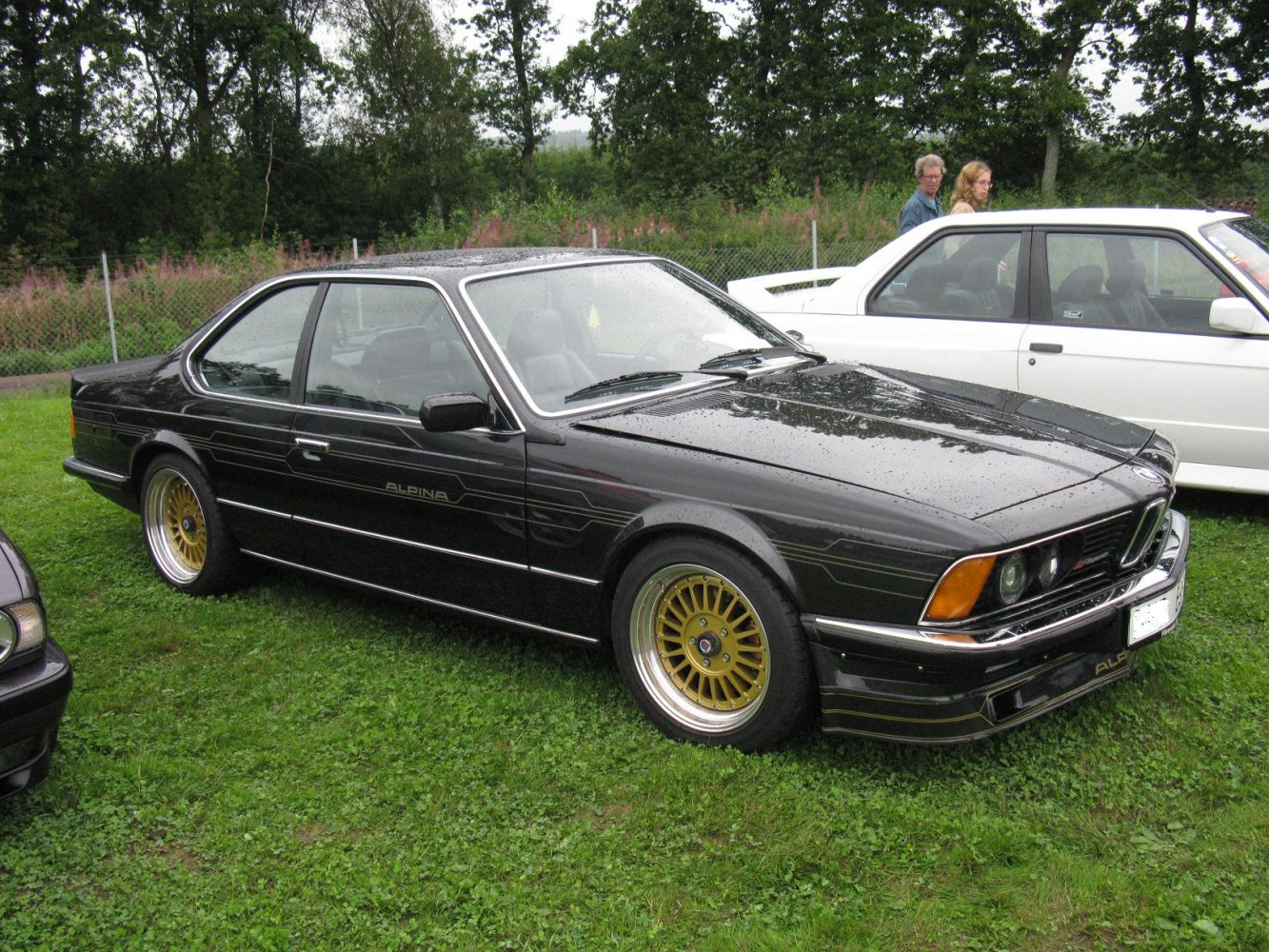 Black coupe with gold alloy wheels and side stripe details