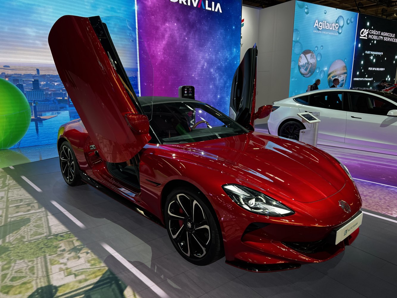 Red sleek coupe with scissor doors open in showroom