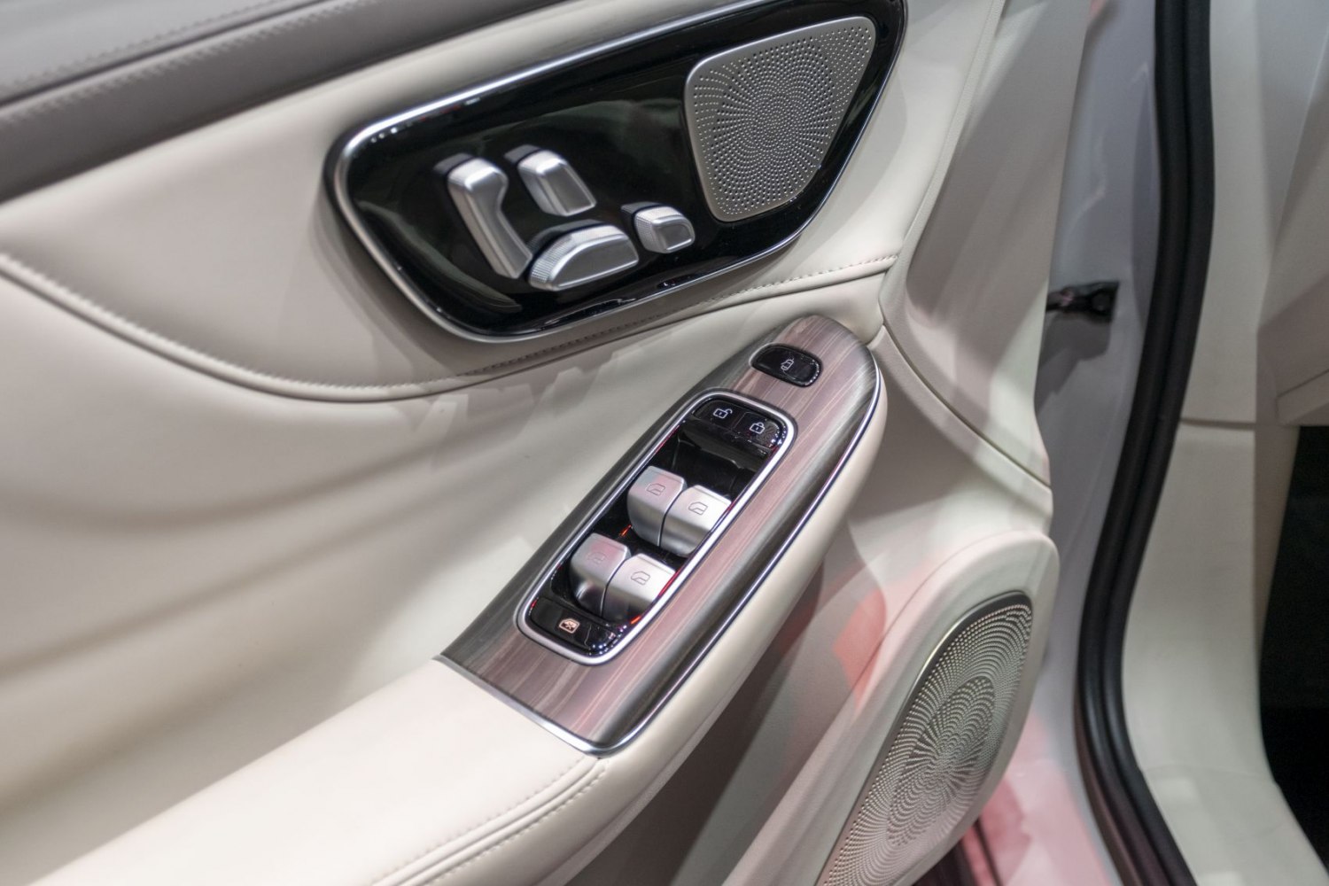 Car door panel with seat controls, window switches, and speakers