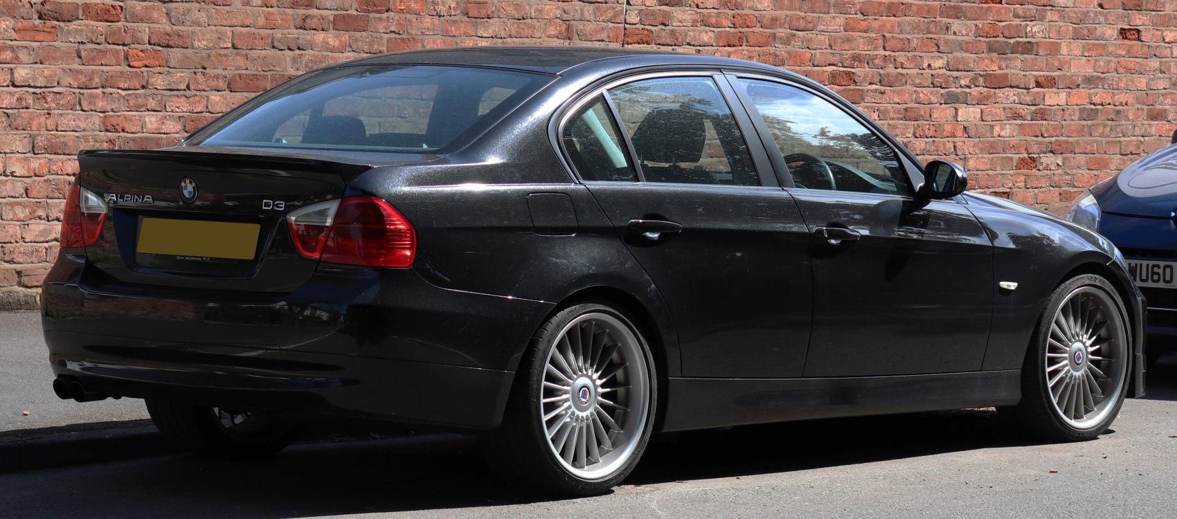 Black luxury sedan rear side with multi-spoke alloy wheels and rear spoiler