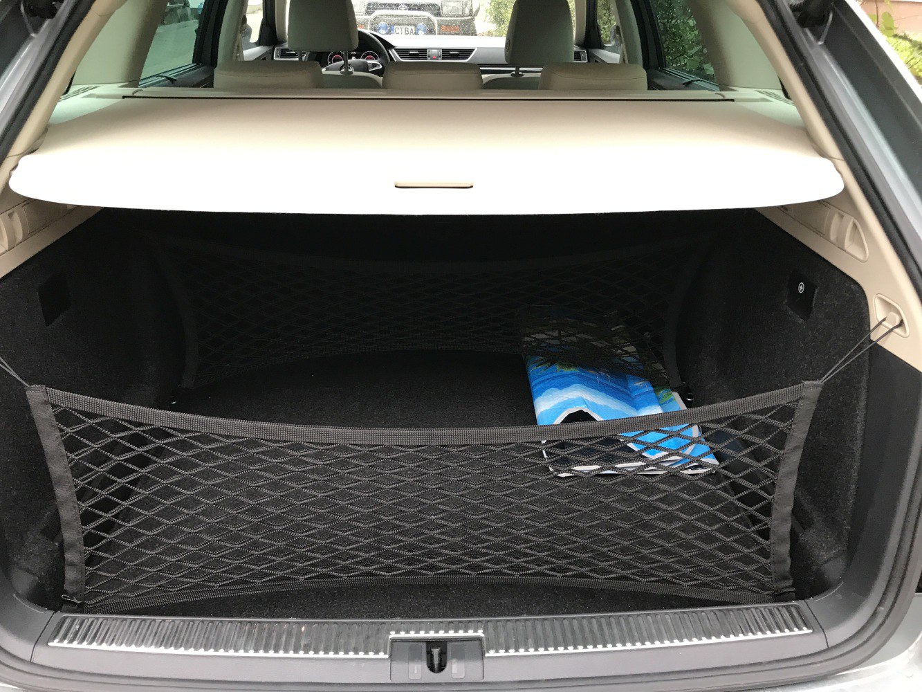 Luggage compartment with cargo net and retractable cover