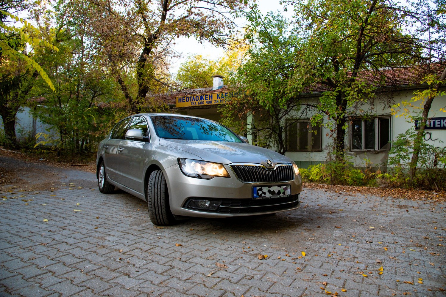 Silver sedan front with LED headlights on paved autumn road