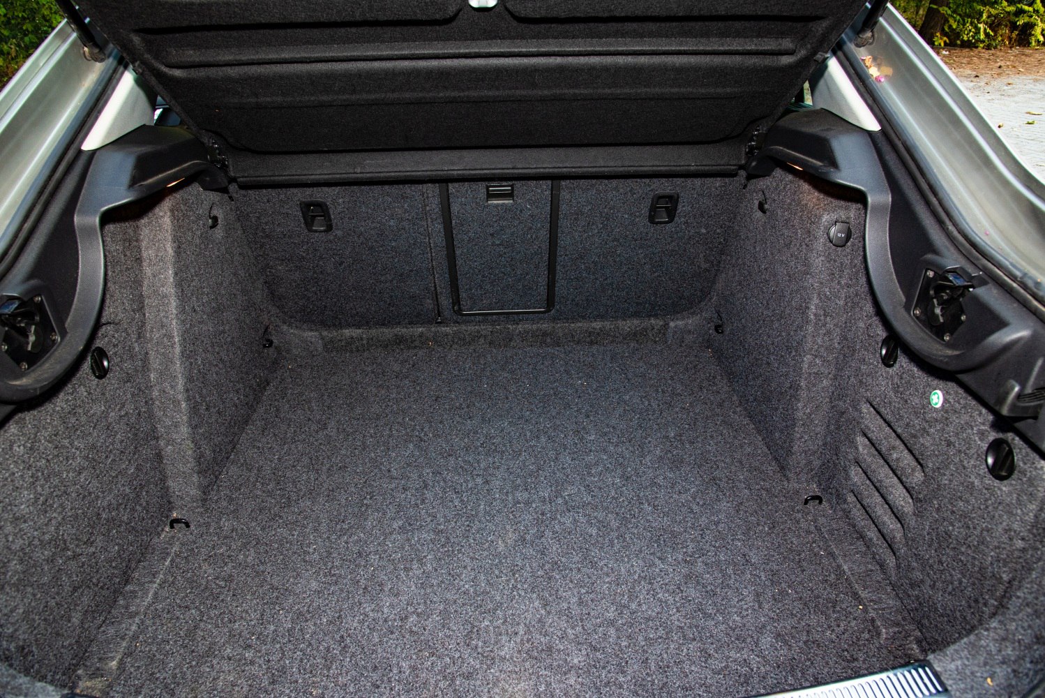 Spacious rear trunk interior with dark carpeting and hooks