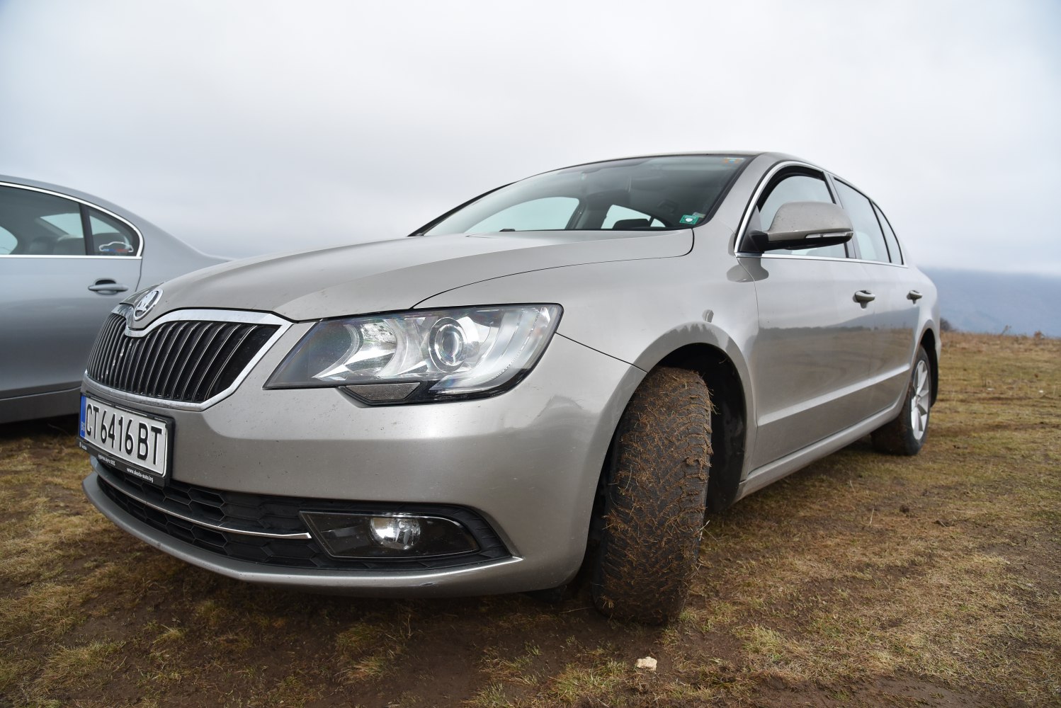 Car front end with headlights and muddy off-road tire