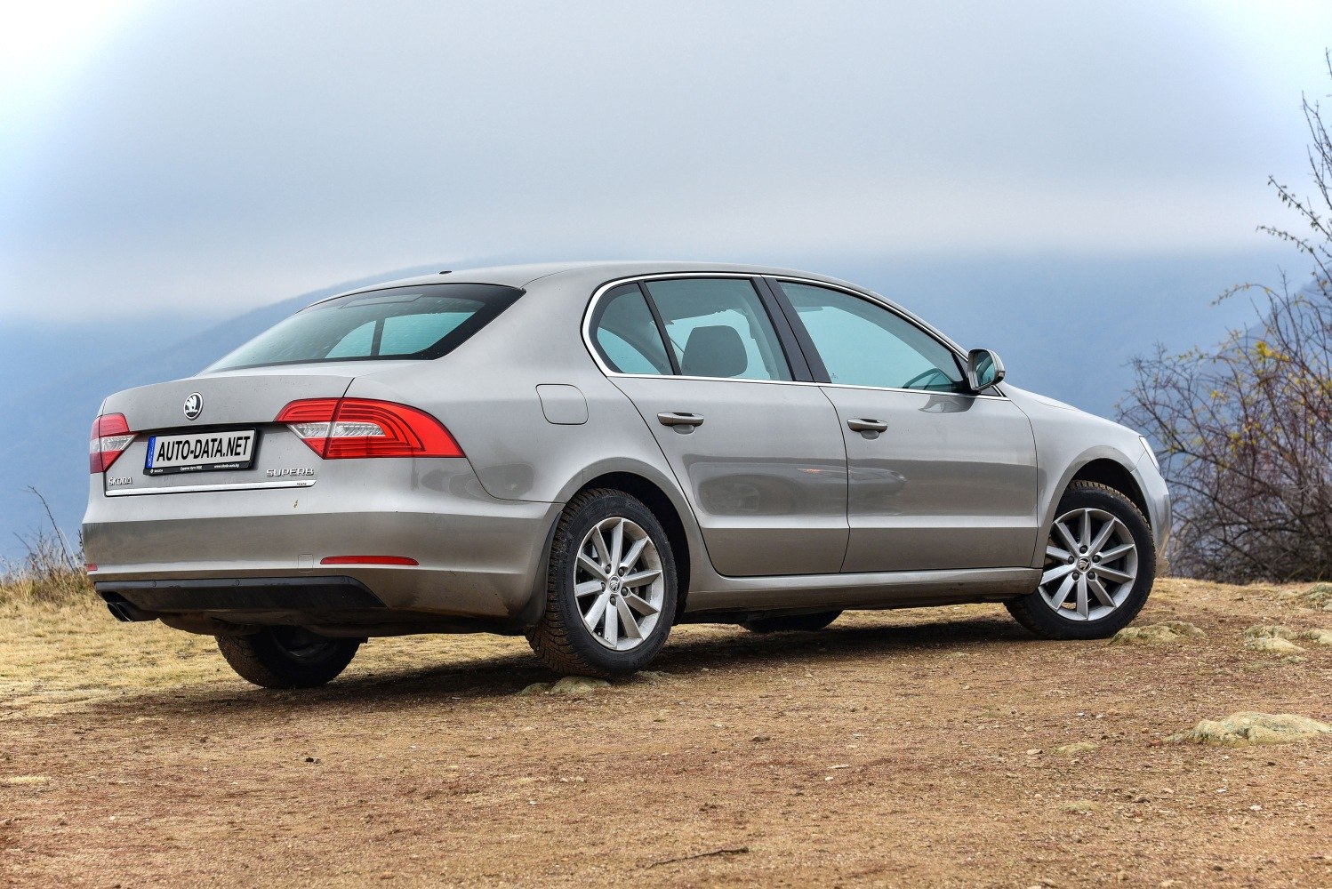 Rear-side view of mid-size sedan with alloy wheels on rough terrain