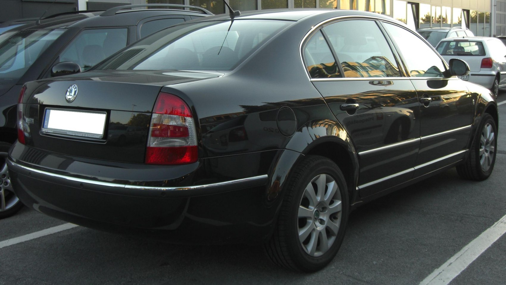 Rear side view of black sedan with distinctive taillights and chrome trim